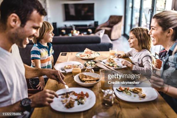 jeune famille heureuse parlant tout en déjeunant à la table à manger. - happy family eating photos et images de collection