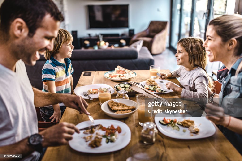 Young happy family talking while having lunch at dining table.