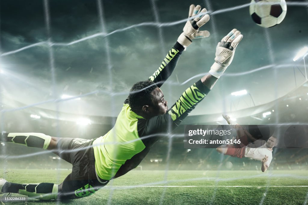Soccer goalkeeper in action at professional stadium.