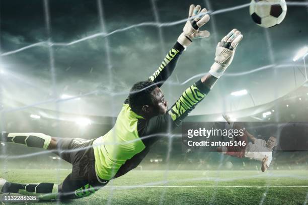 soccer goalkeeper in action at professional stadium. - scoring stock pictures, royalty-free photos & images