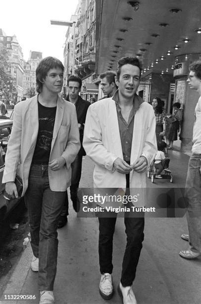 Joe Strummer of The Clash talks to 'Sounds' music journalist Dave McCullough with Mick Jones and Paul Simonon behind, Leicester Square, London, 6th...