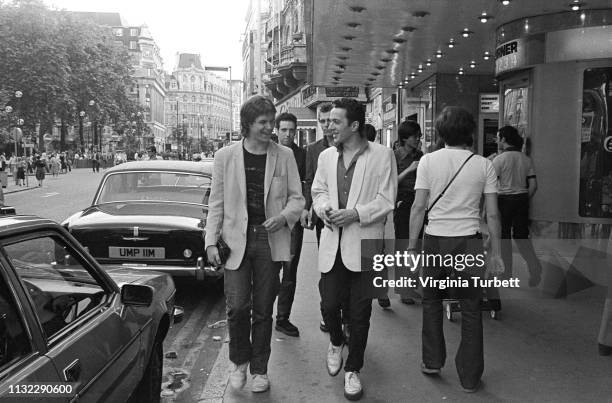 Joe Strummer of The Clash talks to 'Sounds' music journalist Dave McCullough with Mick Jones and Paul Simonon behind, Leicester Square, London, 6th...