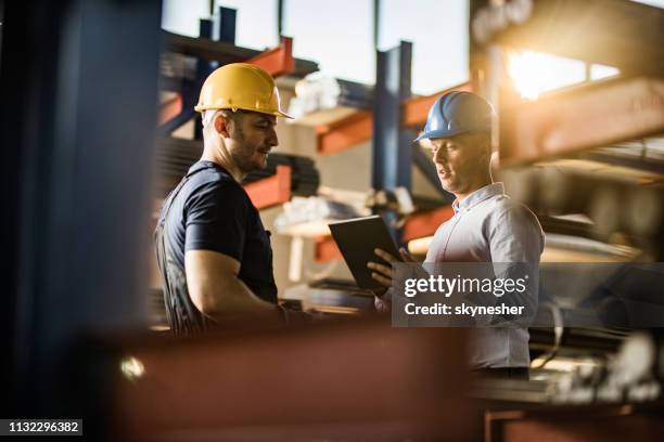quality control inspector using touchpad while talking with metal worker in aluminum mill. - construction owner stock pictures, royalty-free photos & images