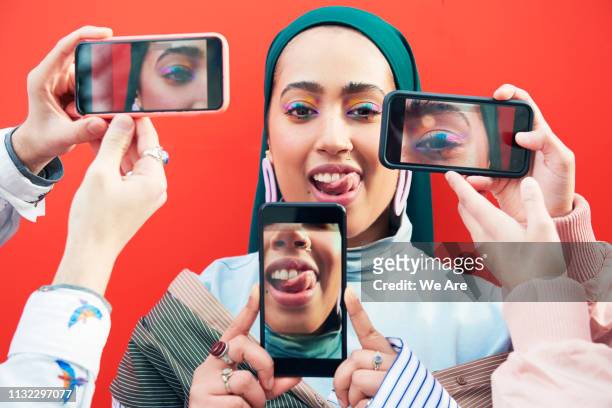 young woman surrounded by smartphones. - portrait femme fond rouge adulte photos et images de collection