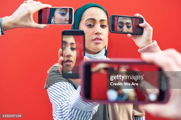 young woman having photo taken by multiple smartphones. - fame stock pictures, royalty-free photos & images