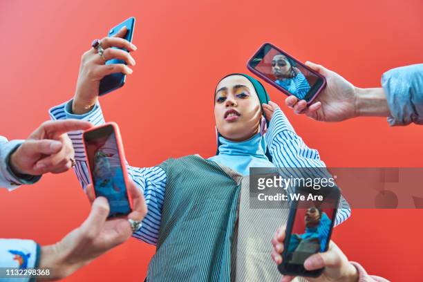 young woman having picture taken by multiple smartphones. - celebrità foto e immagini stock