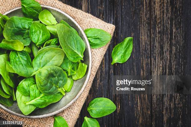 fresh spinach leaves in bowl on rustic wooden table - leaf vegetable stock pictures, royalty-free photos & images