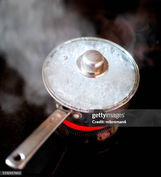 pot boil over. food boiling in utensil at kitchen - bollito foto e immagini stock