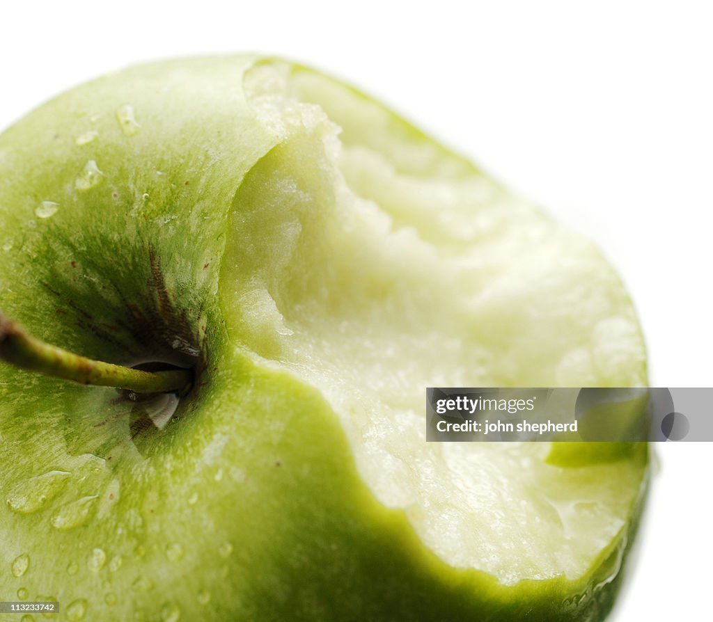 Ripe crisp juicy green apple with chunk missing against white