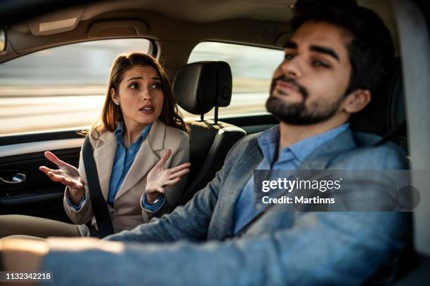en man som kör medan en kvinnlig passagerare füssing om - conversation car bildbanksfoton och bilder