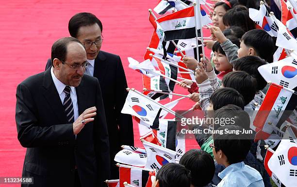Iraqi Prime Minister Nouri al-Maliki and South Korean President Lee Myung-Bak greet South Korean children during a welcoming ceremony held at the...