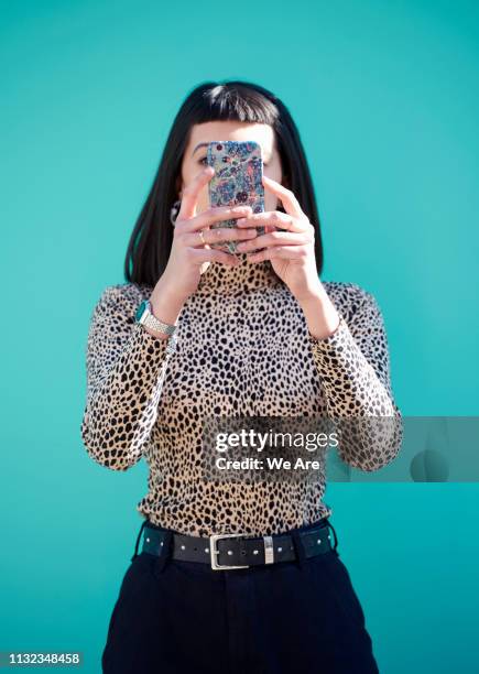 woman obscuring face with smartphone. - obscured face phone stock pictures, royalty-free photos & images