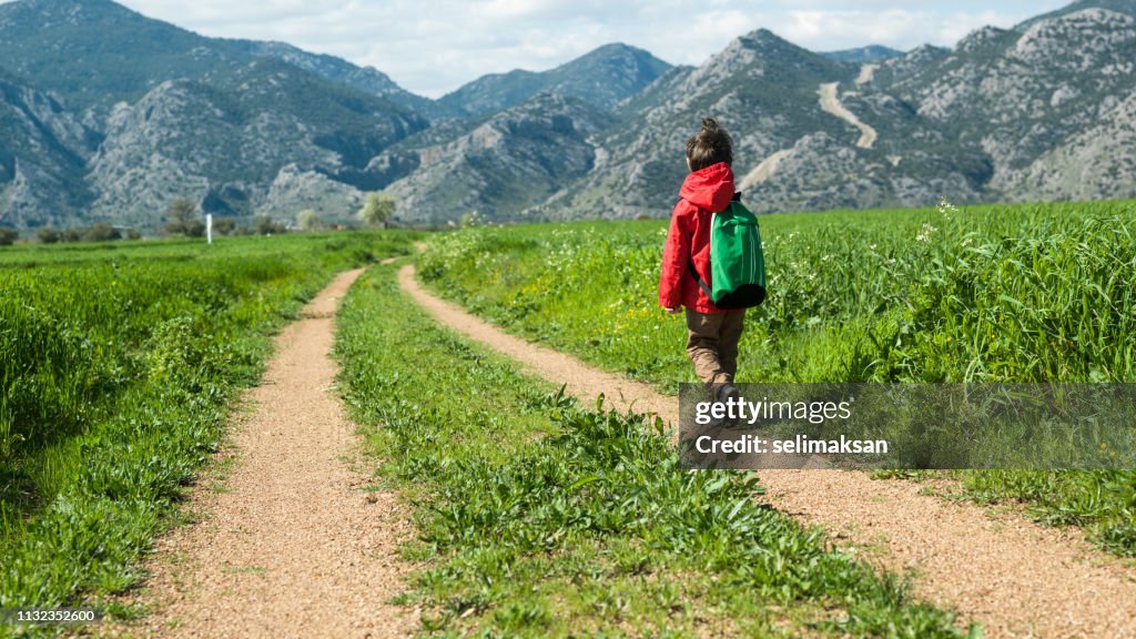 Pequeña escuela niño caminando en tierra camino del país