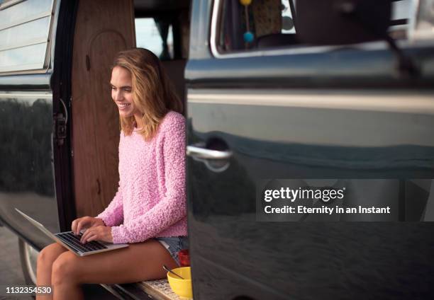 ws young woman sitting in her vintage van using laptop - camping bus stock pictures, royalty-free photos & images