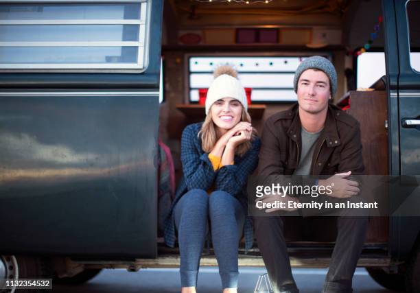young couple sitting in a camper van - camping bus stock-fotos und bilder