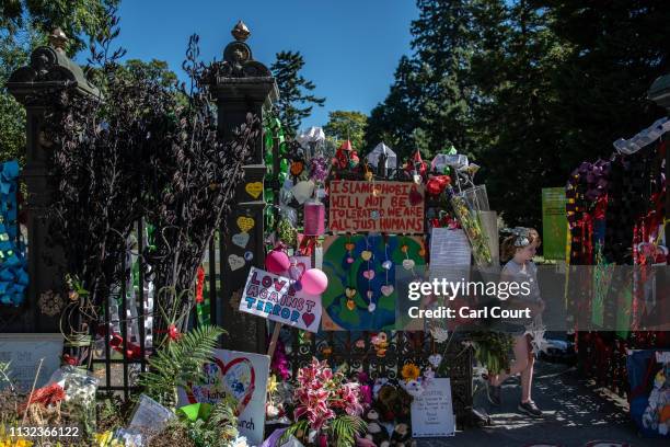 Girl walks through a gate to the botanic gardens that is surrounded by flowers and tributes to victims of the Christchurch mosque attacks, on March...