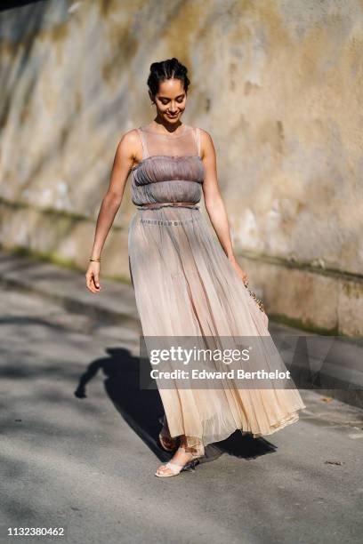 Lana El Sahely wears a Dior pleated mesh lace dress, a pink Lady Dior bag, earrings, outside Dior, during Paris Fashion Week Womenswear Fall/Winter...