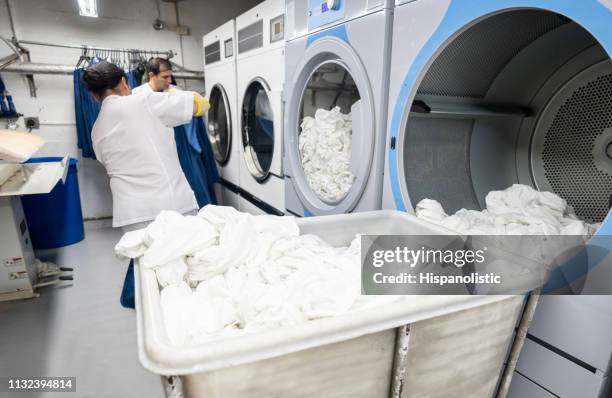 latin american men working together loading a washing machine at a laundry service - dry cleaner stock pictures, royalty-free photos & images