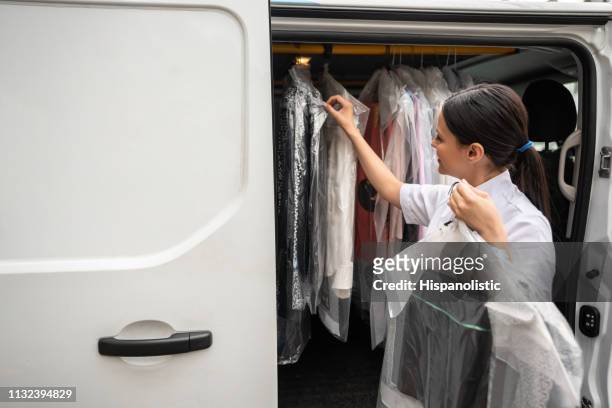 vrouw leveren droge gereinigde kleding - wasserette stockfoto's en -beelden