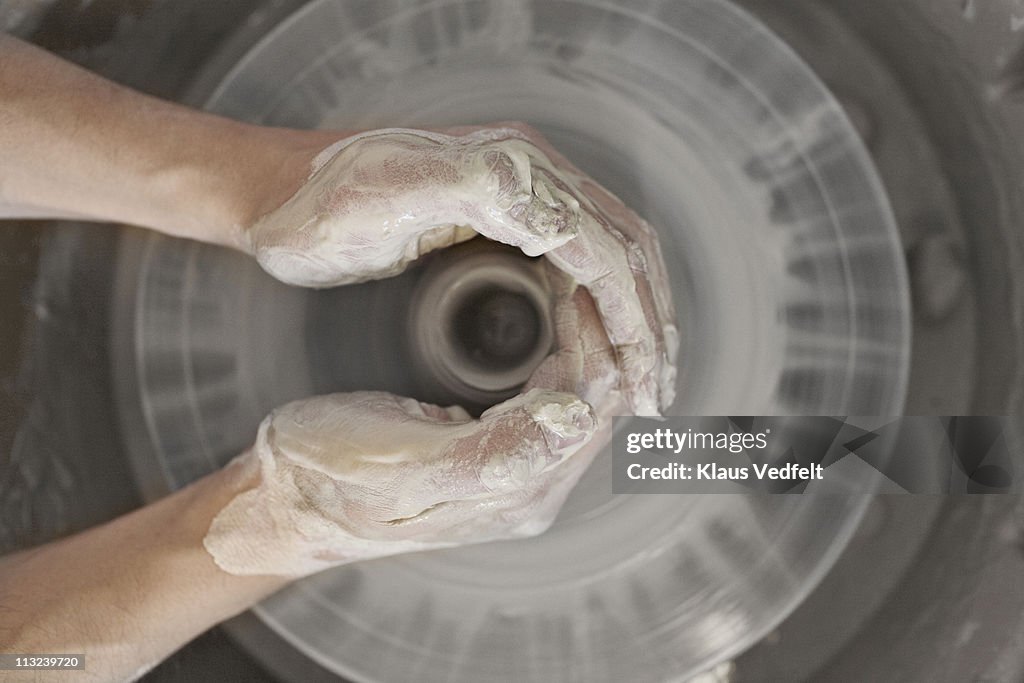 Male hands working with clay on turntable