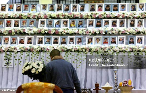 Man offers a flowers at a stand which displays portraits of Okawa Elementary School pupils during the joint memorial service at Iinokawa Daini...