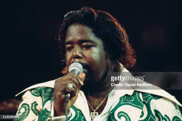 Barry White , U.S. Soul singer, singing into a microphone during a live concert performance, circa 1975.