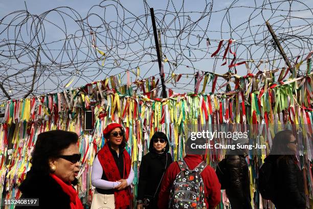 Visitors walk past prayer ribbons wishing for reunification of the two Koreas on the wire fence at the Imjingak Pavilion, near the demilitarized zone...