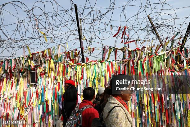 Visitors walk past prayer ribbons wishing for reunification of the two Koreas on the wire fence at the Imjingak Pavilion, near the demilitarized zone...