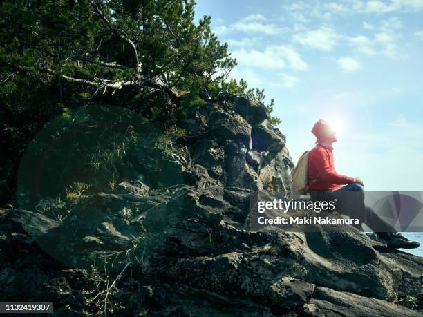 senior men are sitting on rocks and looking down at the sea - satoyama scenery stock pictures, royalty-free photos & images