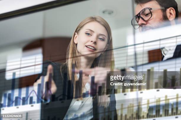 deux personnes d'affaires devant l'affichage futuriste discutant le graphique financier - human mouth stock photos et images de collection