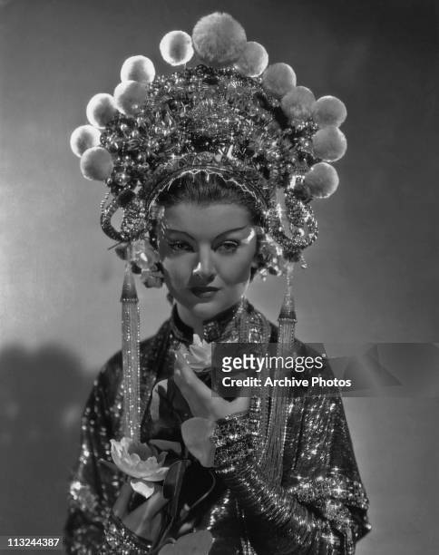 American actress Myrna Loy wearing an elaborate headdress in the 1932 film 'The Mask of Fu Manchu'.
