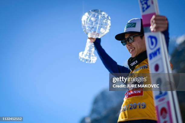 Japan's Ryoyu Kobayashi celebrates with the crystal globe trophy after winning the overall FIS Ski Jumping World Cup in Planica, on March 24, 2019.