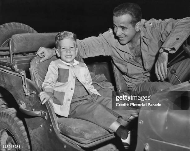 American actor Humphrey Bogart with his son Stephen in a jeep on the set of the 1953 film 'Battle Circus'.