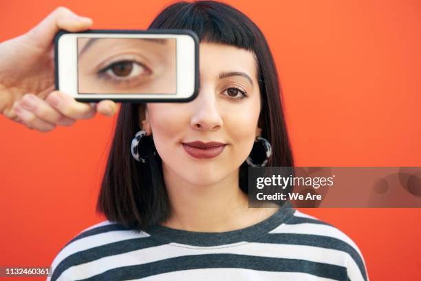 portrait of woman with smartphone over eye. - color blocking stock-fotos und bilder