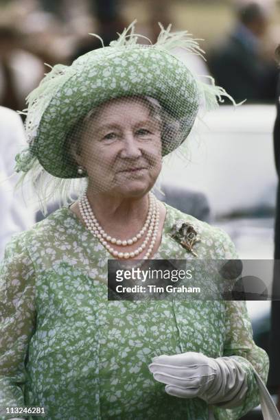 The Queen Mother , wearing a green and white floral print dress with a matching hat decorated wi|th pale green feathers and a net veil, attending the...