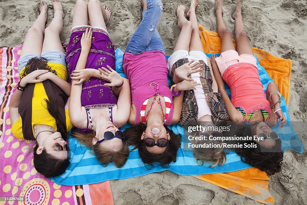 Five teenage girls lying on the beach