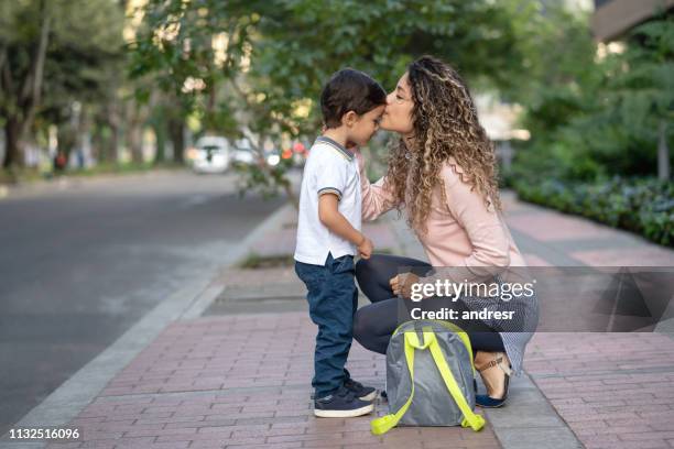 mother kissing her son goodbye while taking him to school - family separation stock pictures, royalty-free photos & images