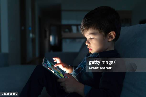 young boy using a digital tablet at home at nighttime - children ipad stock pictures, royalty-free photos & images