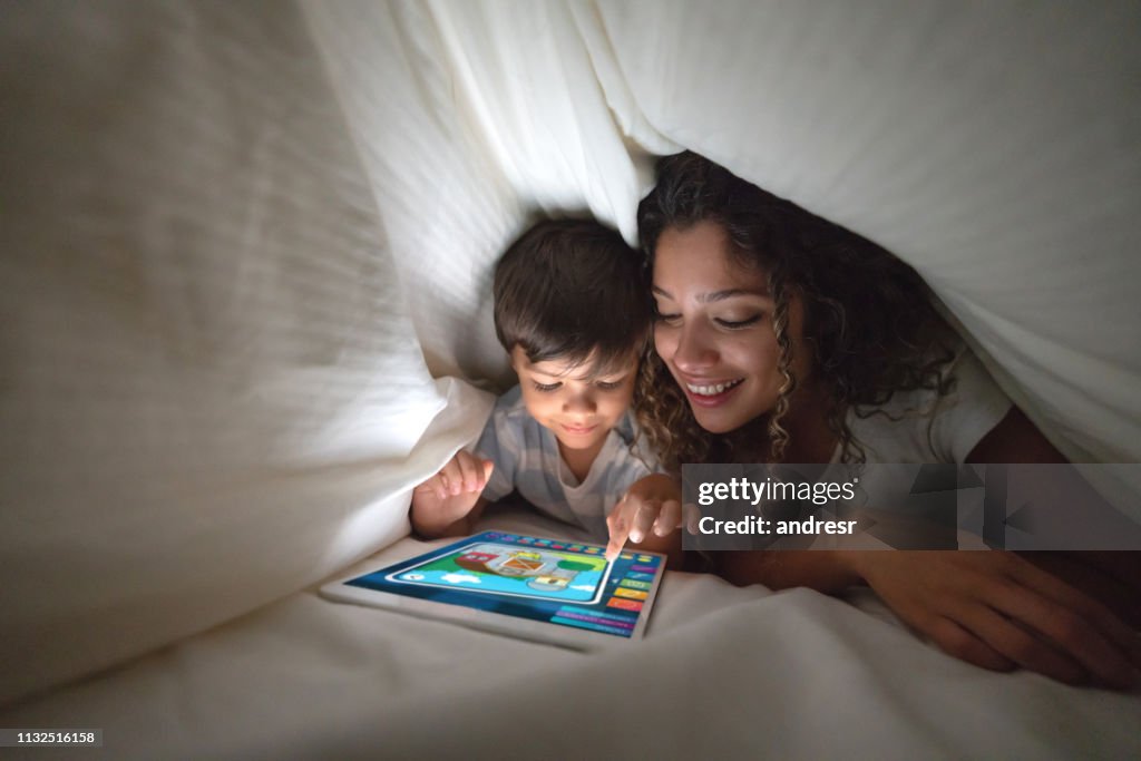 Madre e figlio che giocano su un tablet digitale a letto