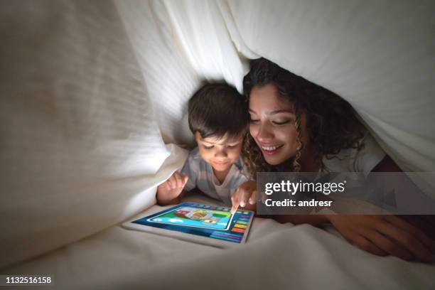 mother and son playing on a digital tablet in bed - family cover stock pictures, royalty-free photos & images