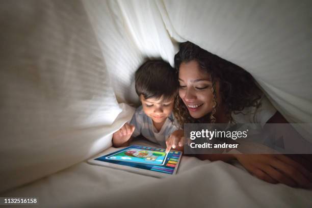 mother and son playing on a digital tablet in bed - family on the internet stock pictures, royalty-free photos & images