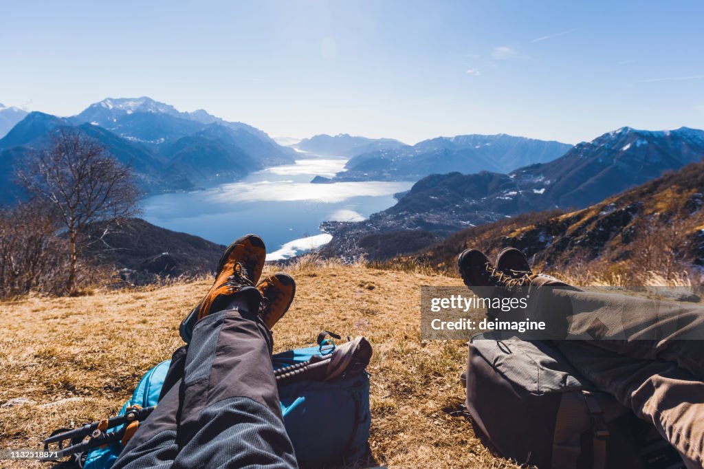 Un par de excursionistas descansando en una colina, lago en el fondo