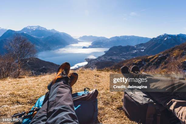 couple of hikers resting on a hill, lake in background - shoes top view stock pictures, royalty-free photos & images