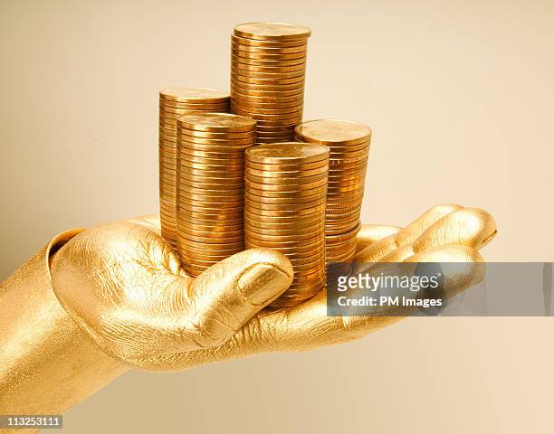 golden hand holding stack of golden coins - body paint stock pictures, royalty-free photos & images