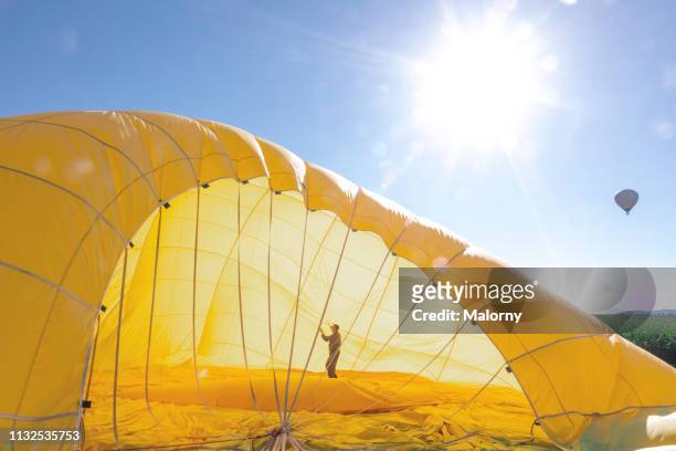 man preparing the yellow envelope of a hot air balloon for take off - hot air balloon ride stock-fotos und bilder