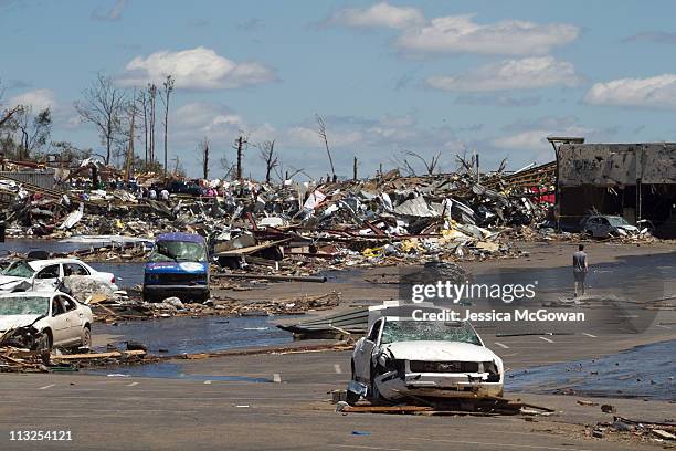 In the aftermath of Wednesday night's storms, a few people traverse through the damage and destroyed cars in a shopping center on McFarland Blvd. On...
