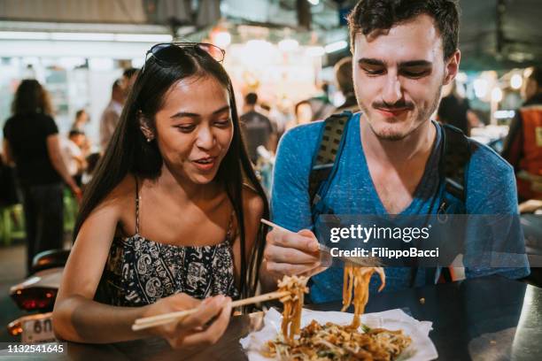 jong paar met diner samen op de avondmarkt - straatvoedsel stockfoto's en -beelden
