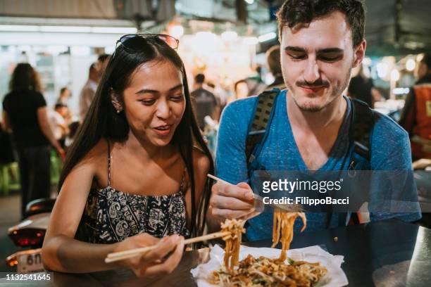 young couple having dinner together at the night market - evening meal restaurant stock pictures, royalty-free photos & images