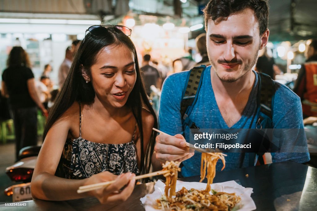 Young couple having dinner together at the night market