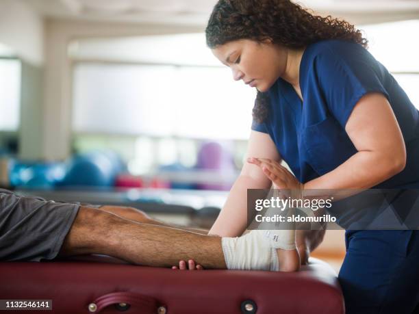 terapeuta ocupacional que sostiene la pierna y el pie del paciente - man touching womans leg fotografías e imágenes de stock